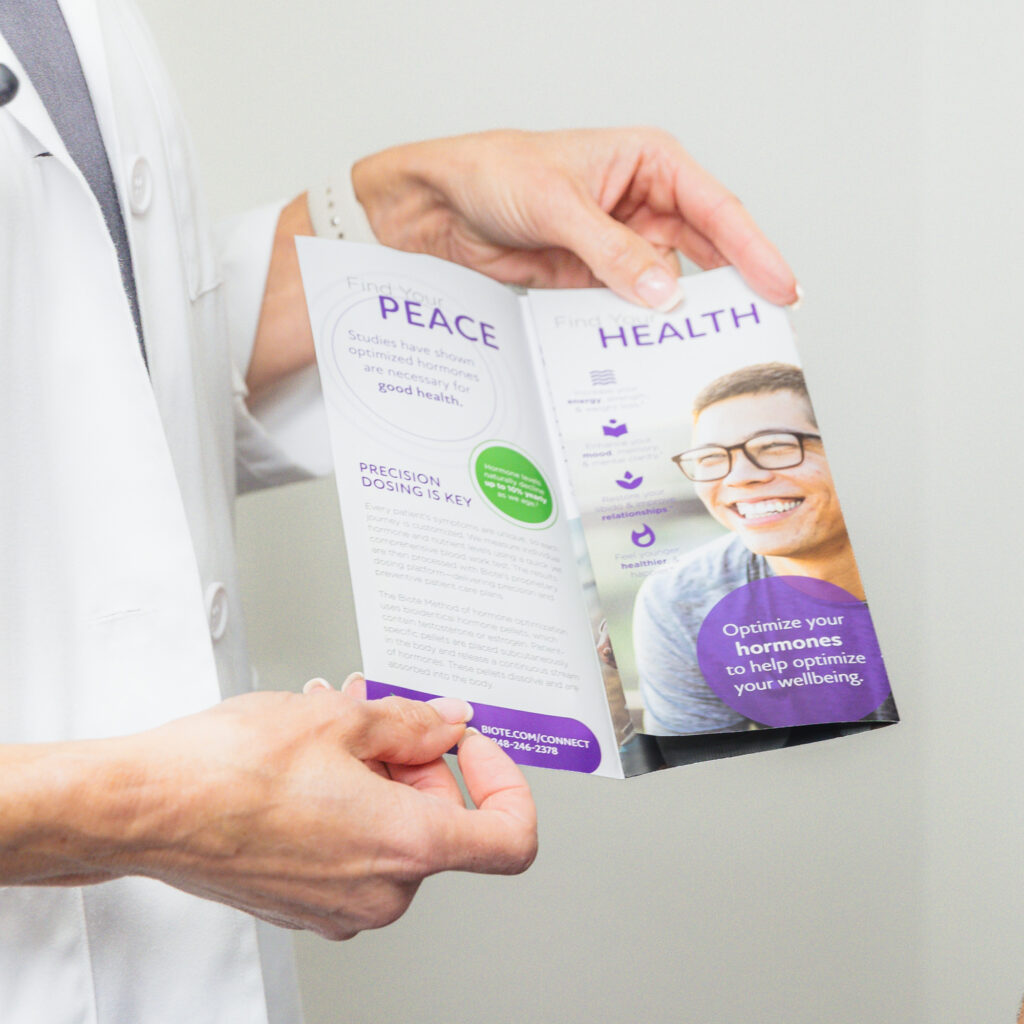 Medical provider holds an informational pamphlet that says 'Peace' and 'Health' in Bold letters to explain the benefits of hormone replacement therapy near The Villages.
