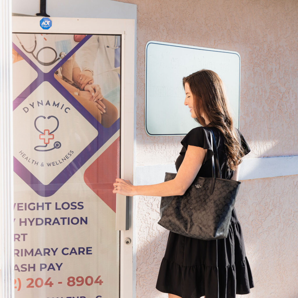 Female patient wearing a dress and holding a purse opens door to Dynamic Health and Wellness to learn more about natural estrogen replacement therapy near The Villages