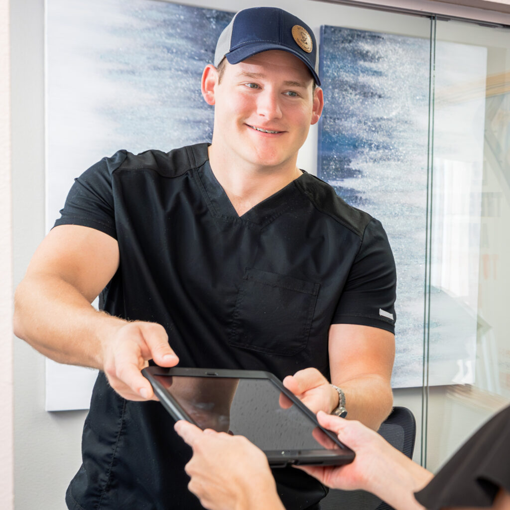 Man wearing a ball cap smiles and hands tablet back to provider before his appointment to learn about treatments to increase testosterone near The Villages