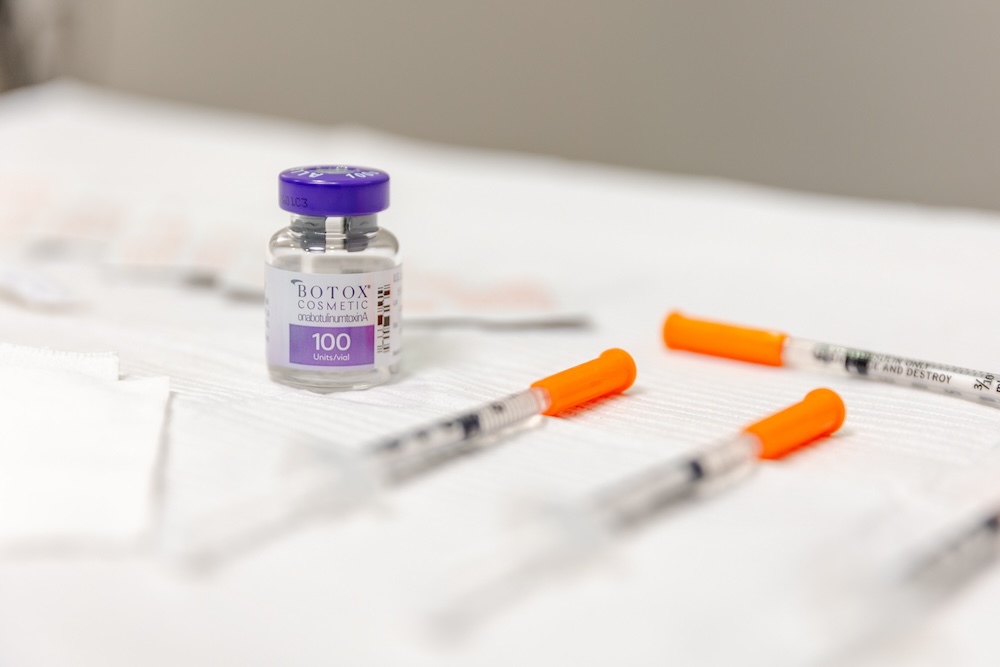 Photo of Botox in Leesburg bottle sitting on a white surface, with syringes laying next to it.